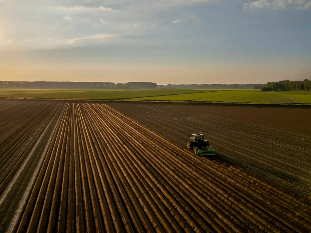 Trator a lavrar um campo ao pôr do sol, agricultura e cooperativas agrícolas transmontanas