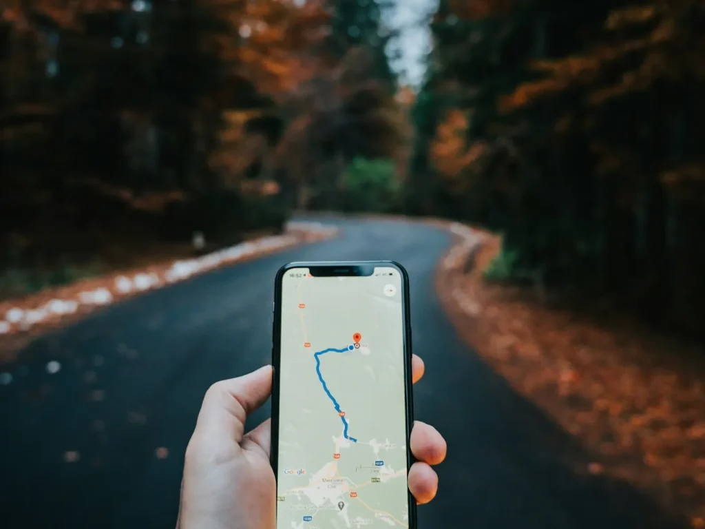 Mão a segurar smartphone com mapa de navegação numa estrada rural, anúncios no Google Maps