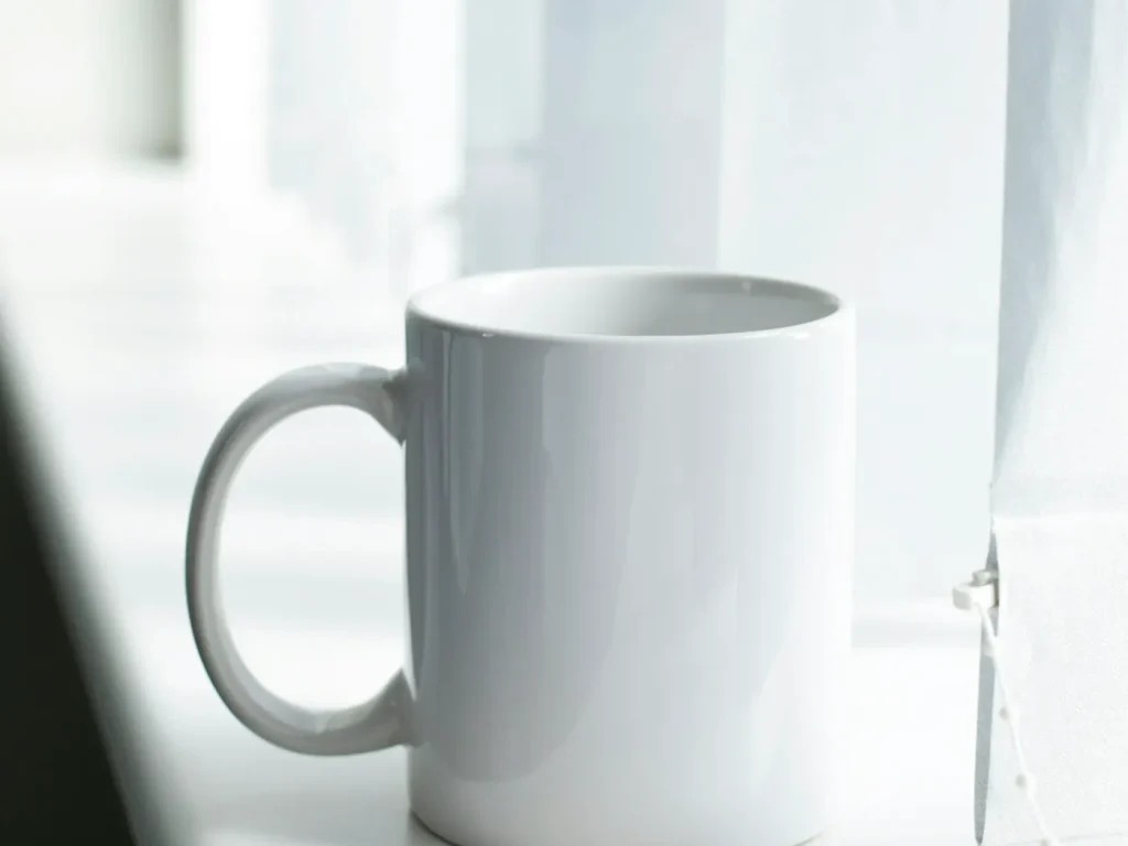 Caneca de cerâmica branca lisa sobre mesa, canecas e garrafas personalizadas com logótipo