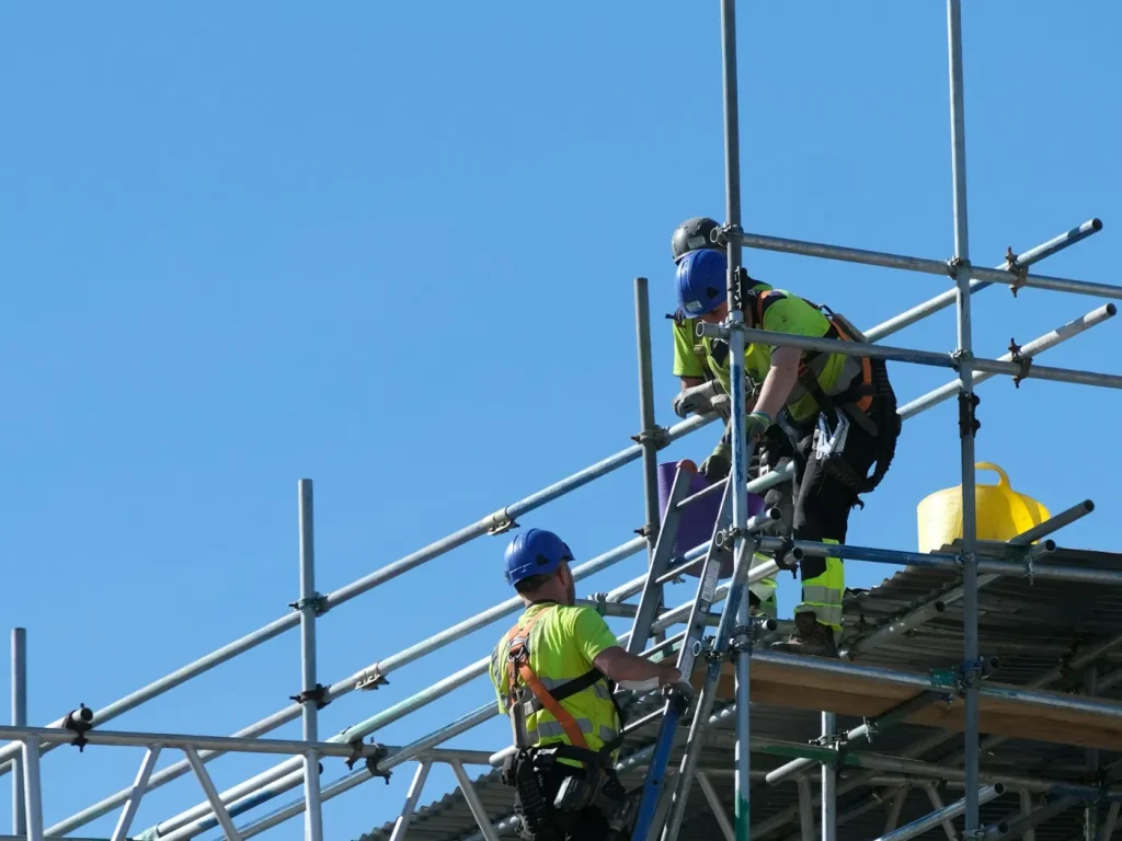 Dois operários da construção a trabalhar em andaimes num edifício, empreiteiros e construção civil em Bragança
