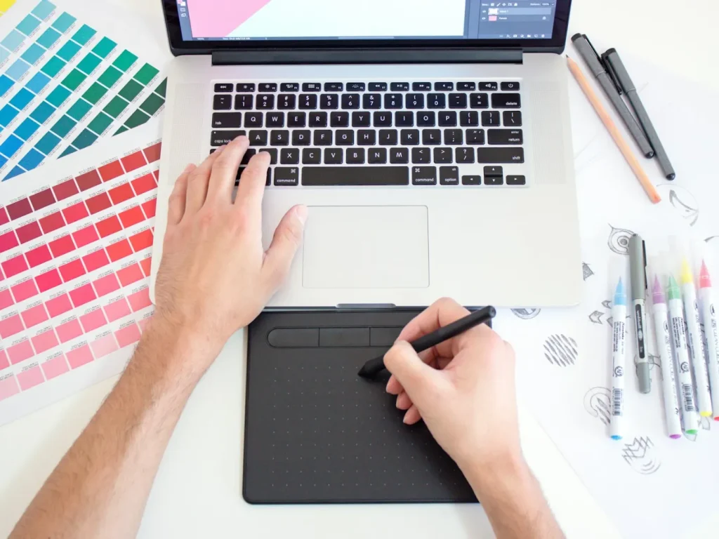 Designer a usar mesa digitalizadora e portátil com amostras de cor, design gráfico em Bragança