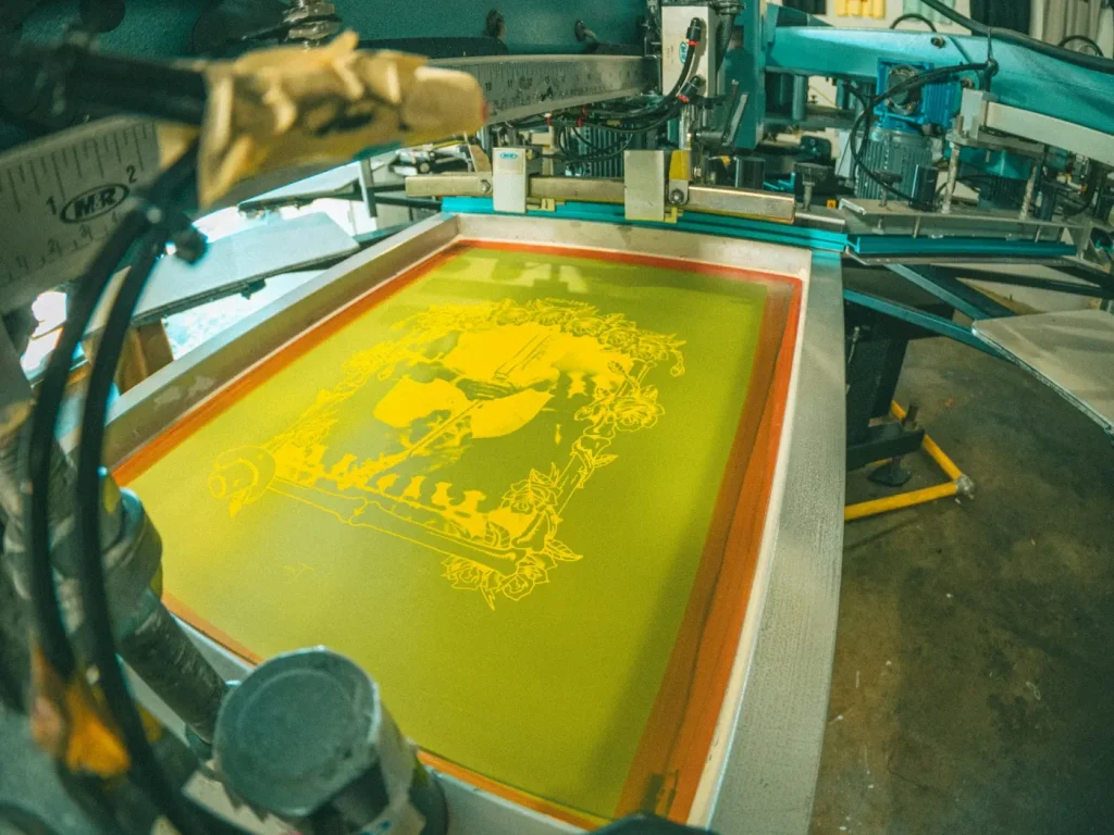 Máquina de serigrafia a estampar desenho com tinta amarela, estampagem de t-shirts em Bragança
