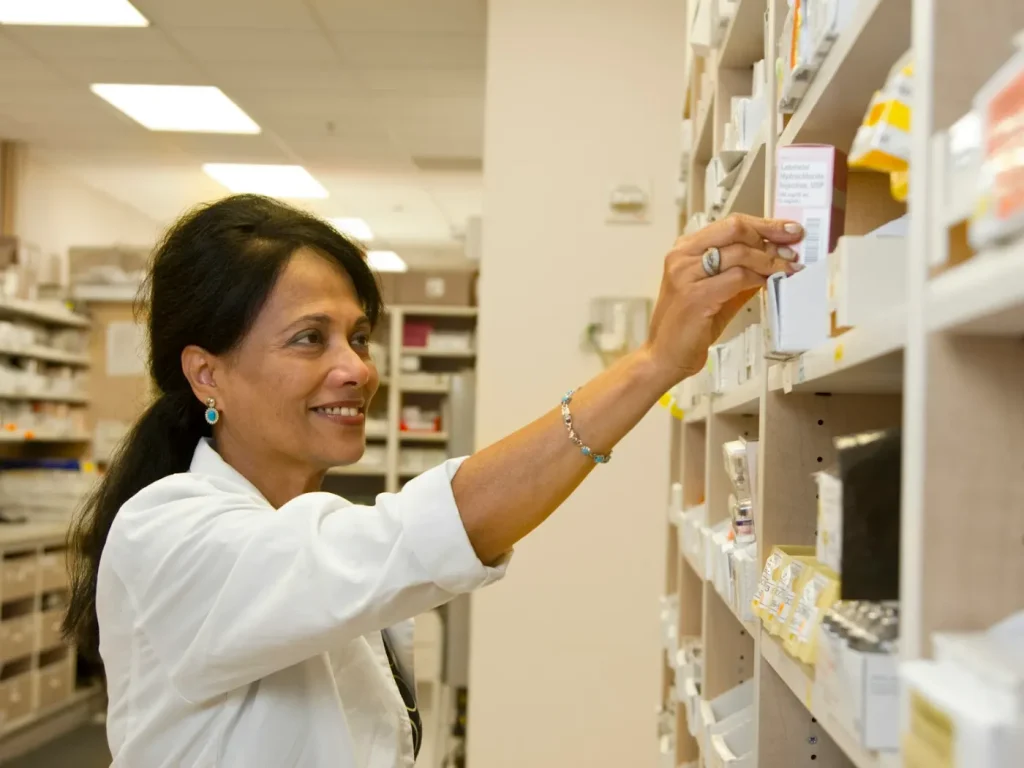 Farmacêutico de bata branca retira medicamento da prateleira, farmácias e parafarmácias em Bragança