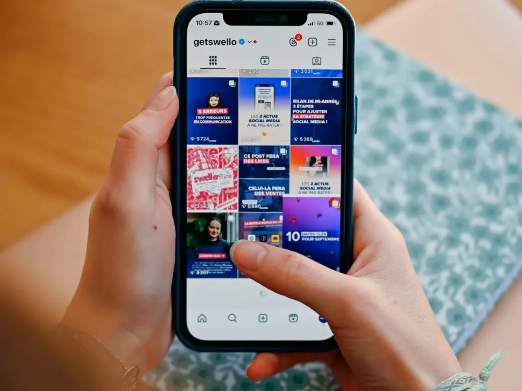 Mãos a percorrer um feed de publicações no telemóvel, gestão de páginas de Facebook