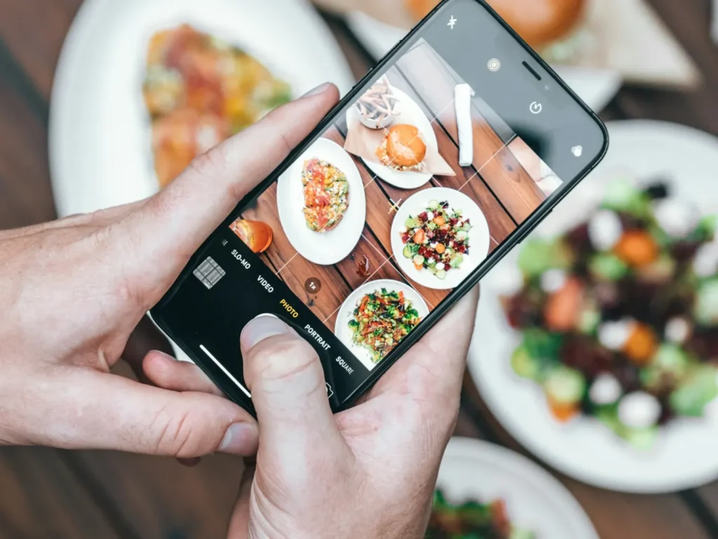 Pessoa a fotografar um prato com o telemóvel para publicar, gestão de Instagram para negócios