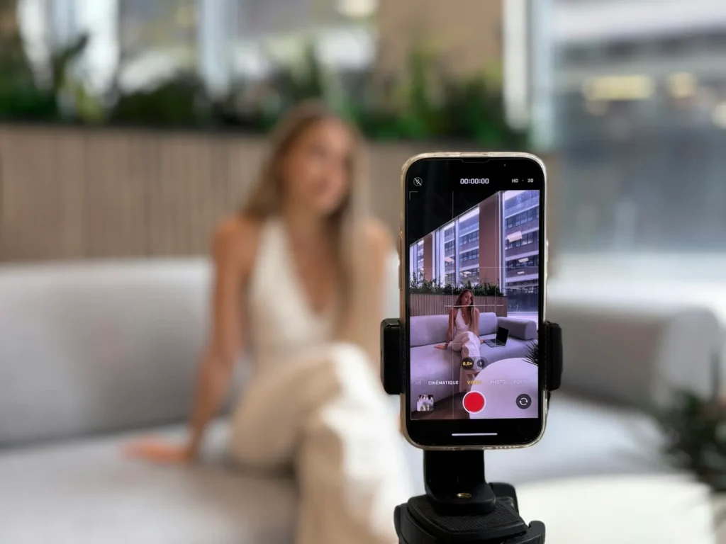 Mulher a gravar vídeo vertical com smartphone num tripé, gestão de TikTok para marcas