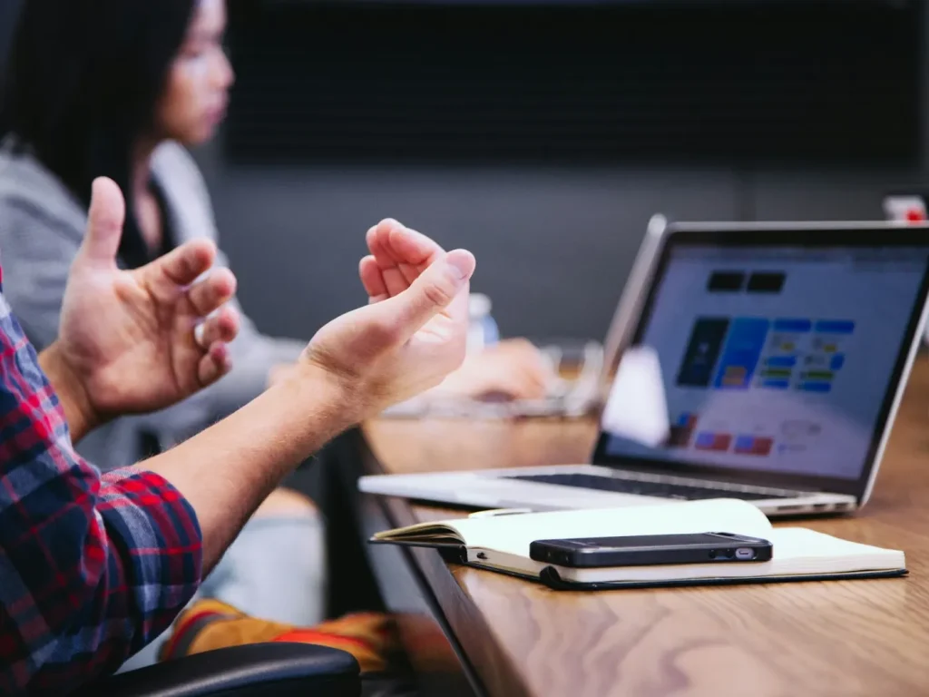 Profissional a gesticular numa reunião de trabalho com portátil, anúncios LinkedIn para empresas