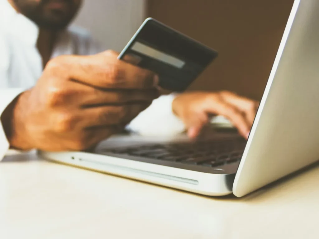 Pessoa com cartão na mão a comprar no portátil, lojas online para negócios de Bragança