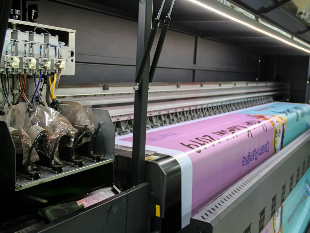 Impressora industrial a imprimir uma lona publicitária comprida em cor-de-rosa, lonas publicitárias em Bragança