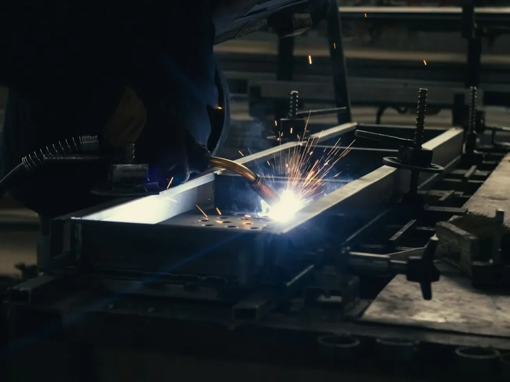 Soldador a trabalhar uma peça de metal numa fábrica, oficinas e indústria em Bragança