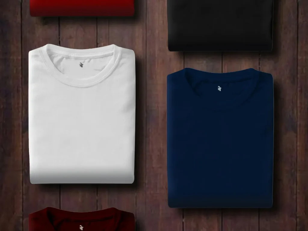 T-shirts dobradas de várias cores sobre painel de madeira, personalização têxtil em Bragança