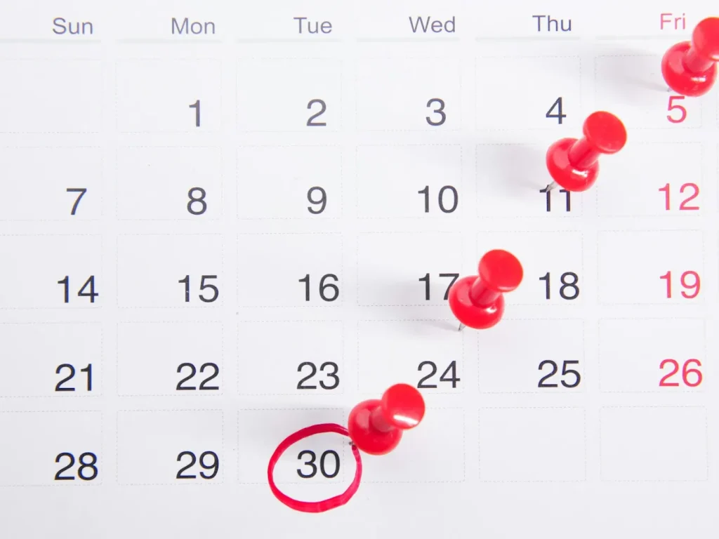 Calendário com pioneses vermelhos para planear publicações, produção de conteúdo mensal para empresas