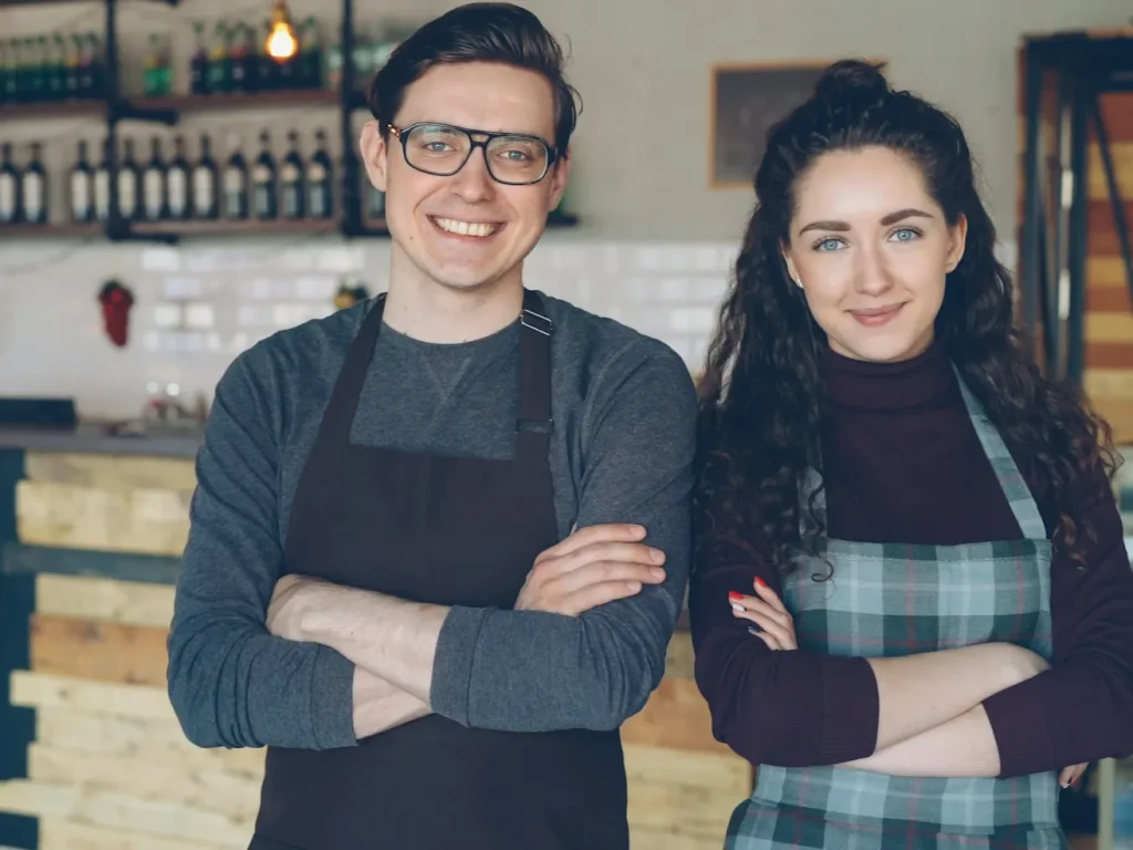 Dois proprietários sorridentes à porta do seu café, pequenos negócios locais em Trás-os-Montes
