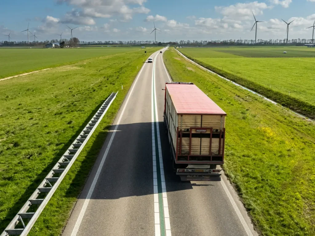 Camião de mercadorias numa estrada rural entre campos e eólicas, transportes e logística em Trás-os-Montes