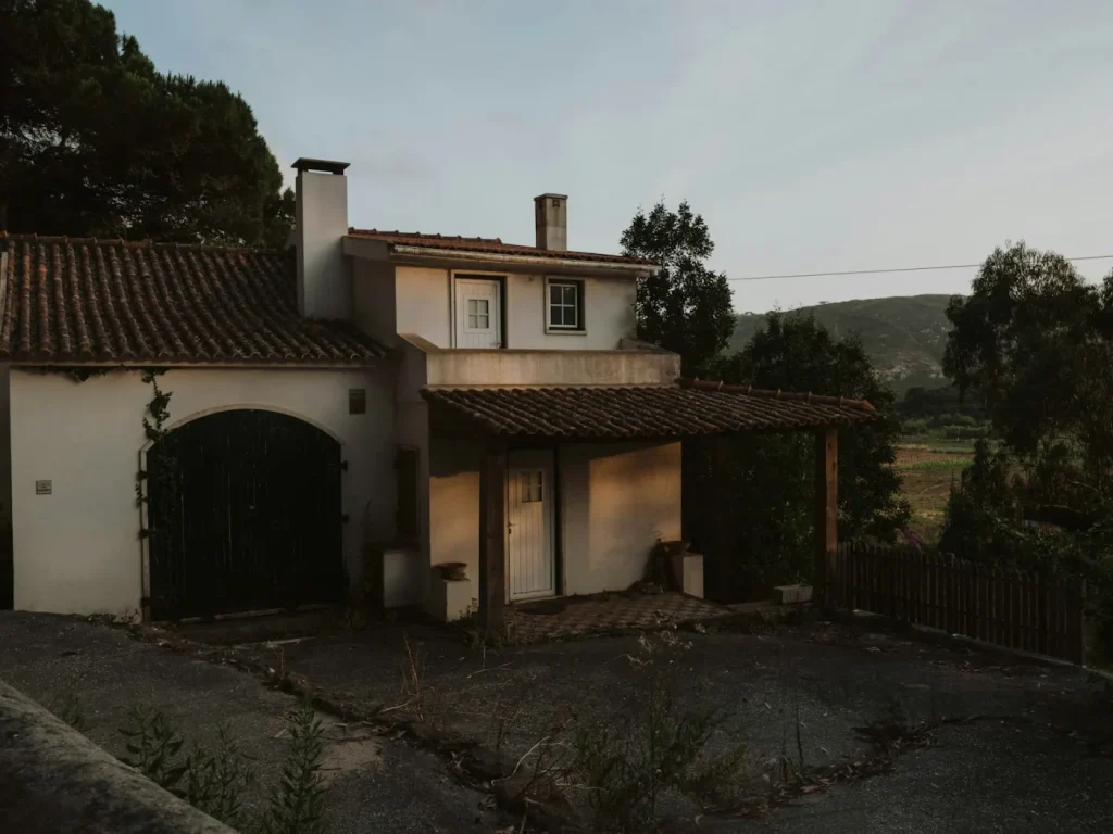 Casa rústica rodeada de árvores no campo, divulgação de turismo rural e alojamento local transmontano