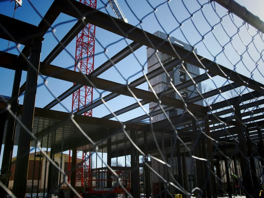 Estaleiro de construção visto através de vedação metálica, vedações de obra com lona mesh